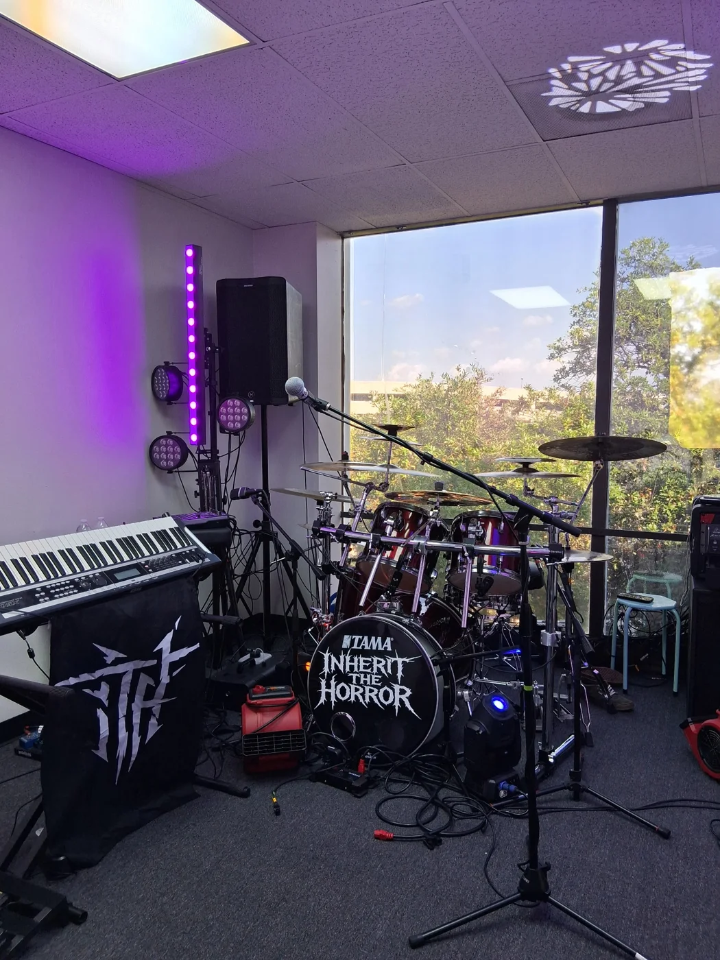 A musician’s rehearsal setup with drums and instruments in a windowed room